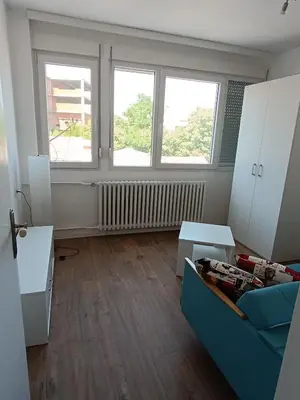 a living room with a couch and two windows at Eli's apartment in Niš