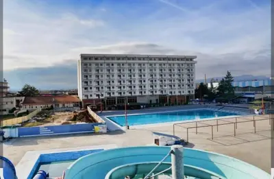 a large building with a swimming pool in front of a building at Apartman Simijonovic in Trnava