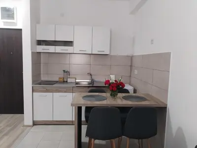 a kitchen with white cabinets and a table with chairs at Apartman Simijonovic in Trnava