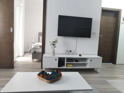 a white living room with a tv on a wall at Apartman Simijonovic in Trnava