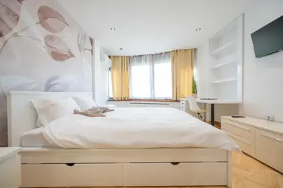a bedroom with a large white bed and a desk at Apartman Simonovic in Vrnjačka Banja