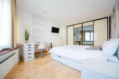 a white bedroom with a large bed and a desk at Apartman Simonovic in Vrnjačka Banja