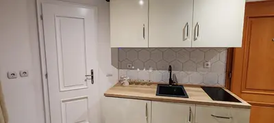 a kitchen with white cabinets and a sink and a door at Apartman Simonovic in Vrnjačka Banja