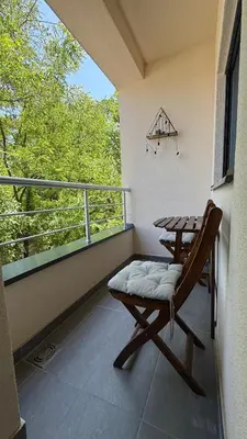 a balcony with a table and a chair and a window at Tajna Ozrena - Sokobanja in Soko Banja