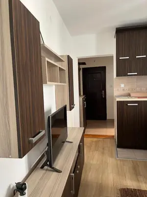 a kitchen with wooden cabinets and a flat screen tv at Na Banjici in Soko Banja