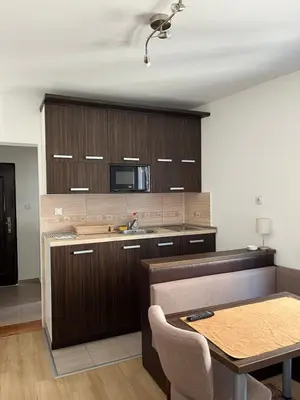 a kitchen with wooden cabinets and a table and a microwave at Na Banjici in Soko Banja