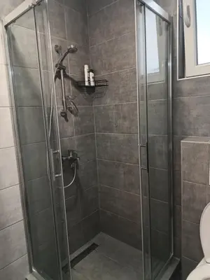 a shower with a glass door in a bathroom at Udoban kutak 1 in Niš