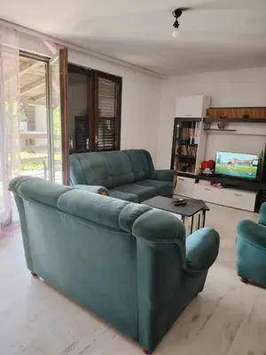 a living room with a green couch and a tv at Vikendica Nina in Bor