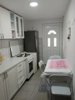 a kitchen with white cabinets and a table and a table and chairs at Sobe Paunović in Soko Banja