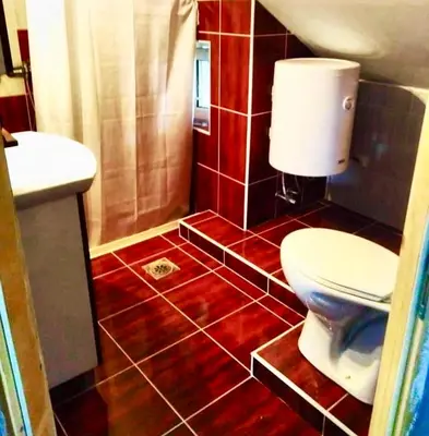 a bathroom with a toilet and a red tiled floor at Apartmani Radovanovic in Soko Banja