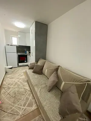 a couch in a living room with a kitchen at Apartman Porodična priča in Vrnjačka Banja