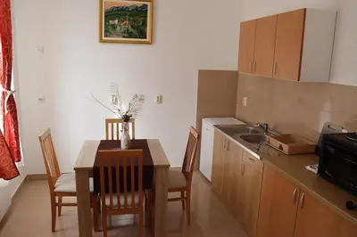 a kitchen with a table and chairs and a kitchen with a sink at Apartmani 