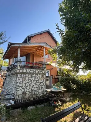 a house behind a stone wall with a table at Kuća za odmor braća Jevtić Vrnjačka Banja in Vrnjačka Banja