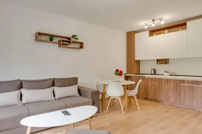 a living room with a couch and a table and a kitchen at Dina LUX apartman in Vrnjačka Banja