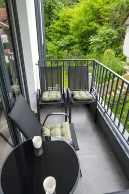 a balcony with two chairs and a table and a window at Dina LUX apartman in Vrnjačka Banja