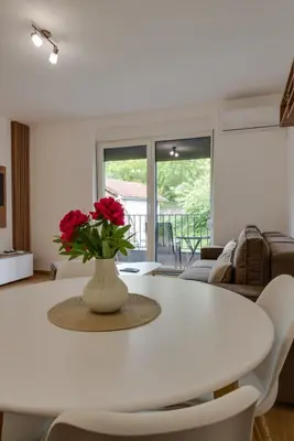a white table with a vase with red flowers on it at Dina LUX apartman in Vrnjačka Banja