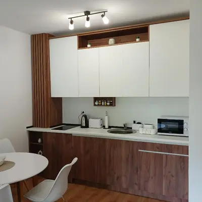 a kitchen with wooden cabinets and a white counter top at Dina LUX apartman in Vrnjačka Banja