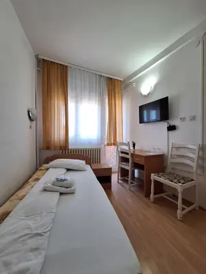 a bedroom with two beds and a table and a desk at Hotel Konaciste Trstenik in Trstenik