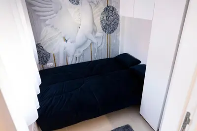 a black bed in a room with white birds on the wall at Apartman A PLUS in Vranje