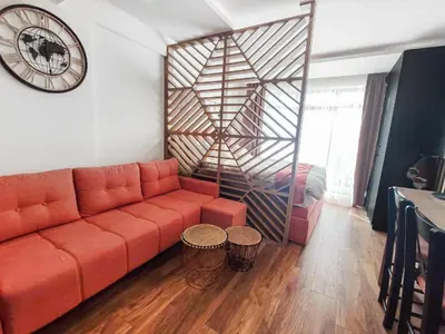 a living room with a orange couch and a clock at Kopaonik,President kop app 404 in Kopaonik