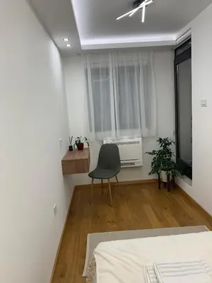 a bedroom with a chair in front of a window at Apartment Jovic in Niš
