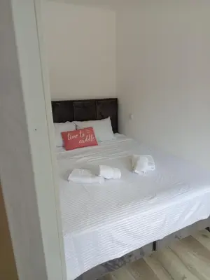 a white bed with a red pillow and towels at Eva Apartman in Prokuplje