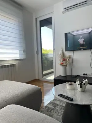 a living room with a table and a tv at Niš Deluxe in Niš