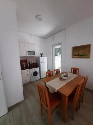 a dining room with a table and chairs and a kitchen at Sunčana oaza in Vrnjačka Banja