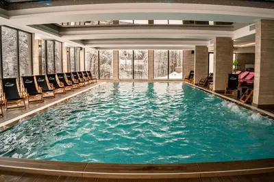 a large swimming pool in a hotel with chairs at Milmari Resort & Spa Kopaonik NLux 72a in Kopaonik