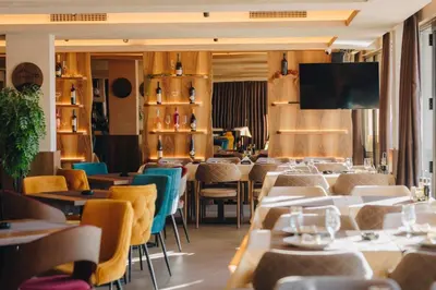 a restaurant with tables and chairs and a flat screen tv at Milmari Resort & Spa Kopaonik NLux 72a in Kopaonik