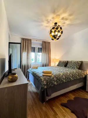 a bedroom with a bed and a television and a chandelier at Apartman My Dream in Vrnjačka Banja
