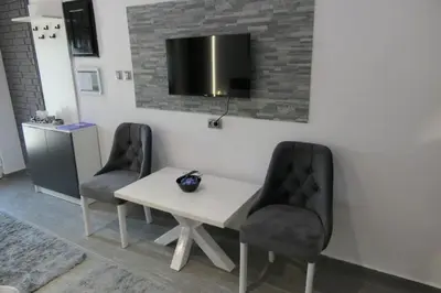 a white table with two chairs and a tv on a wall at Apartman Dzunic in Pirot