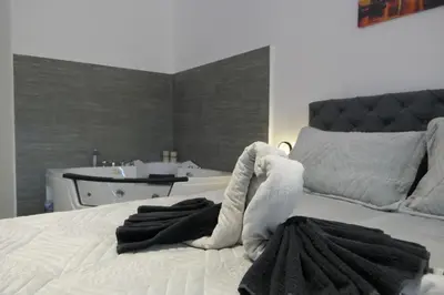 a bedroom with a white bed with a bath tub at Apartman Dzunic in Pirot