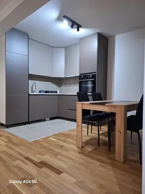 a kitchen with a wooden table and black chairs at Apartman Centrala Lux in Pirot