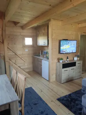 a kitchen in a log cabin with a flat screen tv at Kuća Pored Sunca in Kruševac