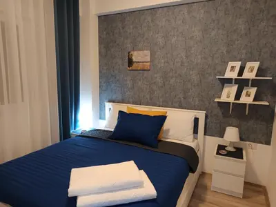 a bedroom with a blue bed and a gray wall at AquaBlue Jagodina in Jagodina