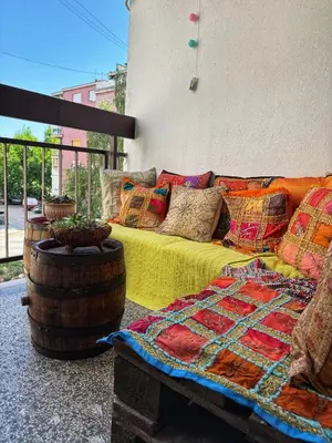 a bed with colorful pillows sitting next to a barrel at spazio in Knjazevac.