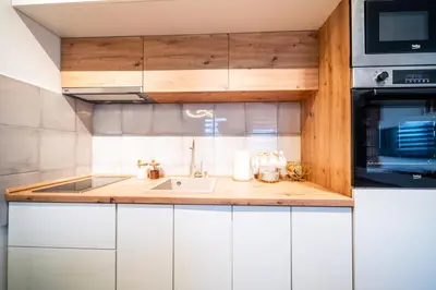 a kitchen with white cabinets and a sink and a microwave at Todorović Lux Vrnjačka Banja in Vrnjačka Banja
