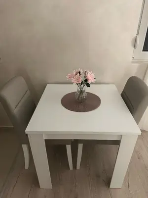 a white table with a vase of flowers on it at Apt 7- Sokobanjica apartmani in Soko Banja