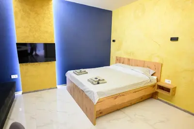 a small bed in a room with blue and yellow walls at Tanja Lux in Niš
