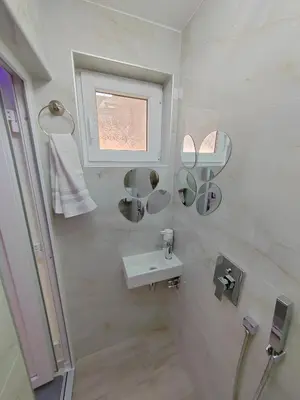 a white bathroom with a sink and a window at Your Place Studio in Niš