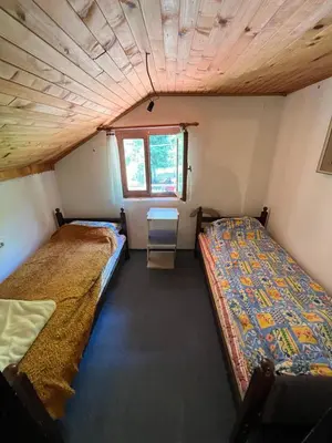 two beds in a small room with a window at Apartmani Radulovic in Kursumlijska Banja