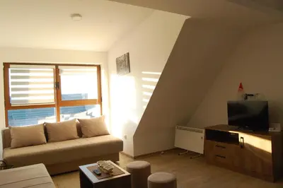 a living room with a couch and a television at Snow Hill Kopaonik in Kopaonik