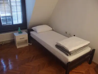 a small room with a bed and a night stand at City Centre Hostel in Niš