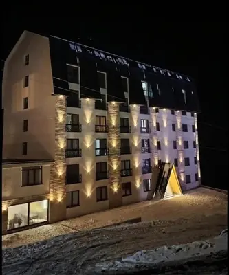 a building with lights on the side of it at night at Kopaonik-President kop apartment 101 free wellness&spa in Kopaonik