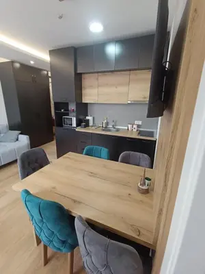 a kitchen with a wooden table and blue chairs at Kopaonik-President kop apartment 101 free wellness&spa in Kopaonik