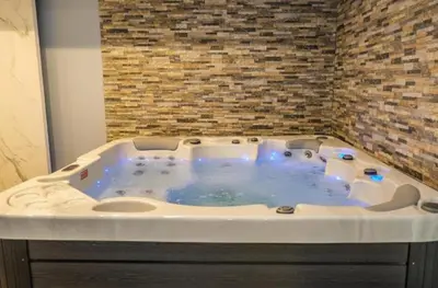 a jacuzzi tub in a room with a brick wall at Kopaonik-President kop apartment 101 free wellness&spa in Kopaonik