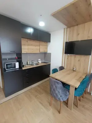 a kitchen with a wooden table and blue chairs at Kopaonik-President kop apartment 101 free wellness&spa in Kopaonik