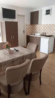 a kitchen with a table and some chairs and a kitchen with a table at Orhideja smeštaj Sokobanja in Lepterija