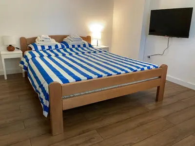 a bedroom with a bed with a blue and white striped sheet at Studio Sanader in Soko Banja